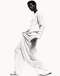 Model in white long-sleeve tunic and wide-leg trousers posing against a bright white background