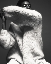 Black and white portrait of a woman in a heavy knitted sweater with voluminous sleeves by Kevin Obrien