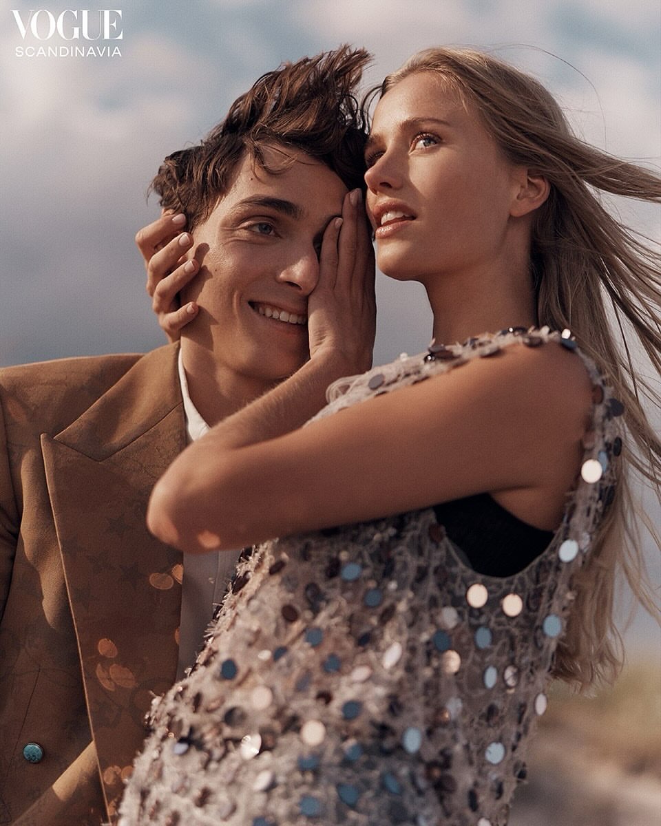 A stylish couple poses outdoors for a Vogue Scandinavia fashion editorial with natural lighting, showcasing modern clothing and elegant design.