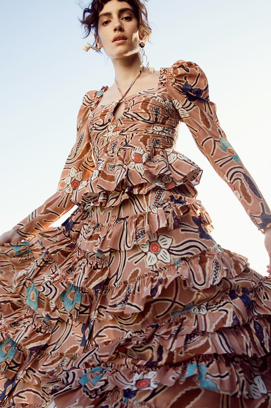Model in patterned tiered dress with puff sleeves posing against a bright sky background styled by Lara Backmender