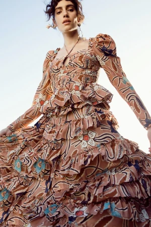 Model in patterned tiered dress with puff sleeves posing against a bright sky background styled by Lara Backmender