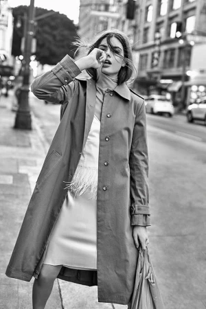 Model in trench coat walking on a city street with hair blowing in the wind in Los Angeles.