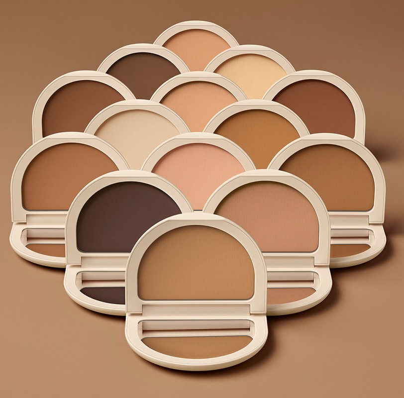 Multiple open and closed compacts displaying makeup foundation shades from light to dark arranged against a complementary background.