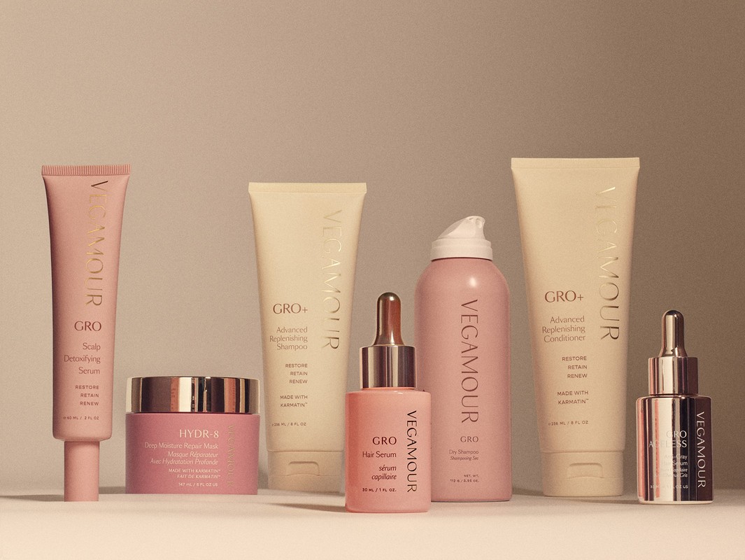 Collection of Vegamour brand hair care and beauty products in various sizes and containers, arranged against a neutral background.