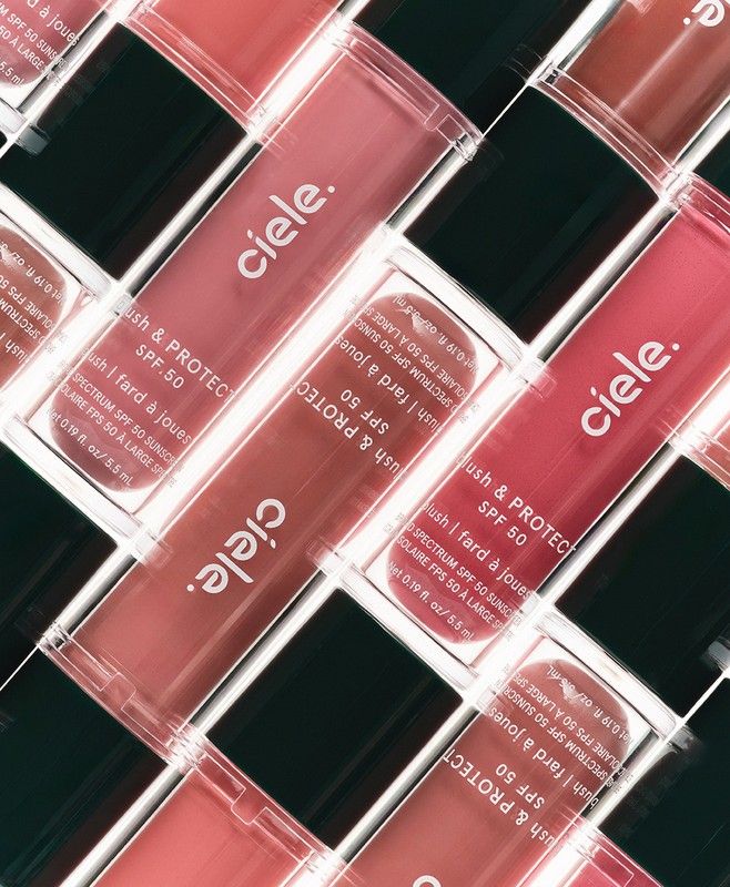 Close-up angled shot of multiple Ciele blush and protect SPF 50 makeup tubes in a repeating pattern with visible text and packaging.