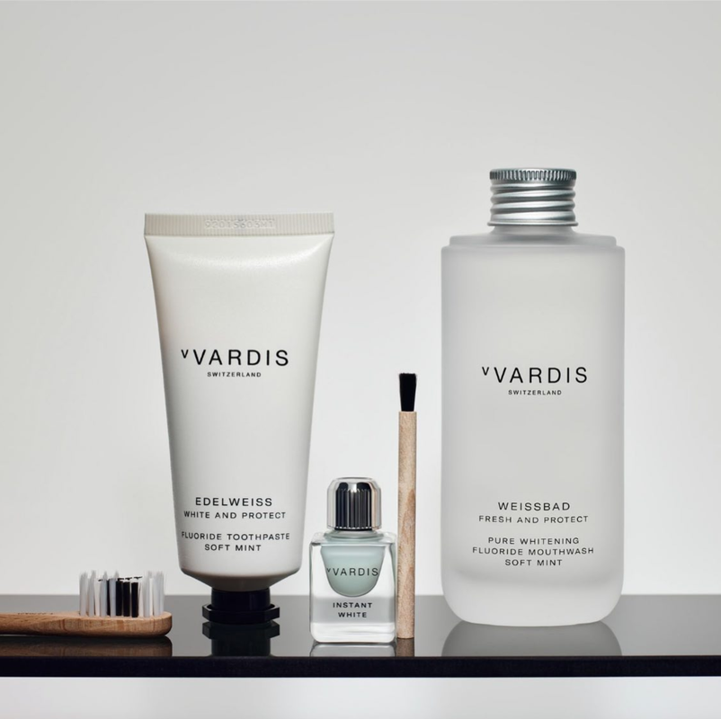 Vardis brand oral hygiene products including toothpaste, mouthwash, brush on a black surface against a white background.