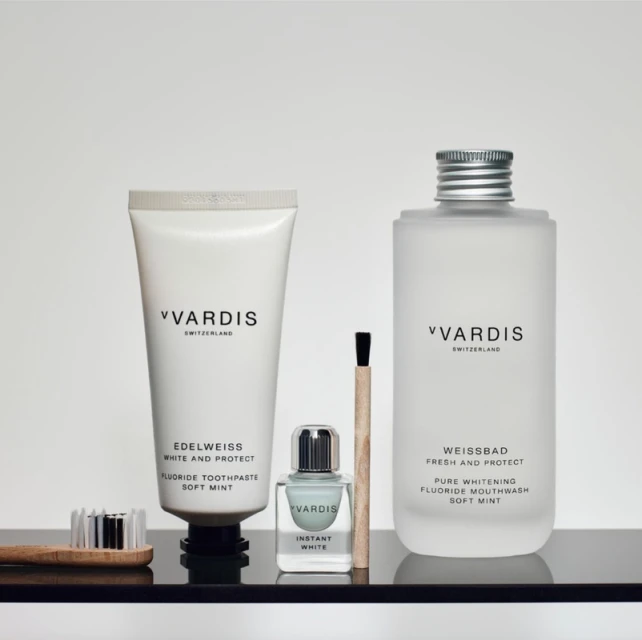 Vardis brand oral hygiene products including toothpaste, mouthwash, brush on a black surface against a white background.