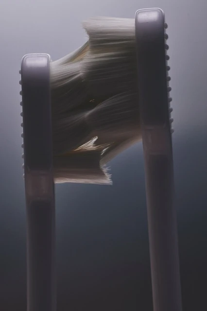 Close-up of a white toothbrush head with worn bristles against a light gray background, showcasing wear and texture detail.