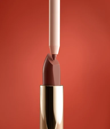 Close-up shot of brown lipstick with gold tube and nude-colored lip liner pointed at the tip, set against a reddish-brown background.