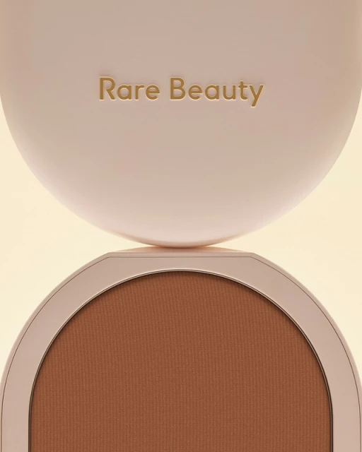 Close-up of a Rare Beauty bronzer compact showing the logo on the lid and the bronzer shade inside, creating a beauty product shot.