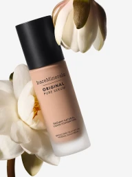 A BareMinerals foundation bottle surrounded by white water lily flowers against a plain white background.
