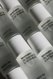 Diagonal arrangement of frosted white deodorant bottles against a pale background with visible branding text.