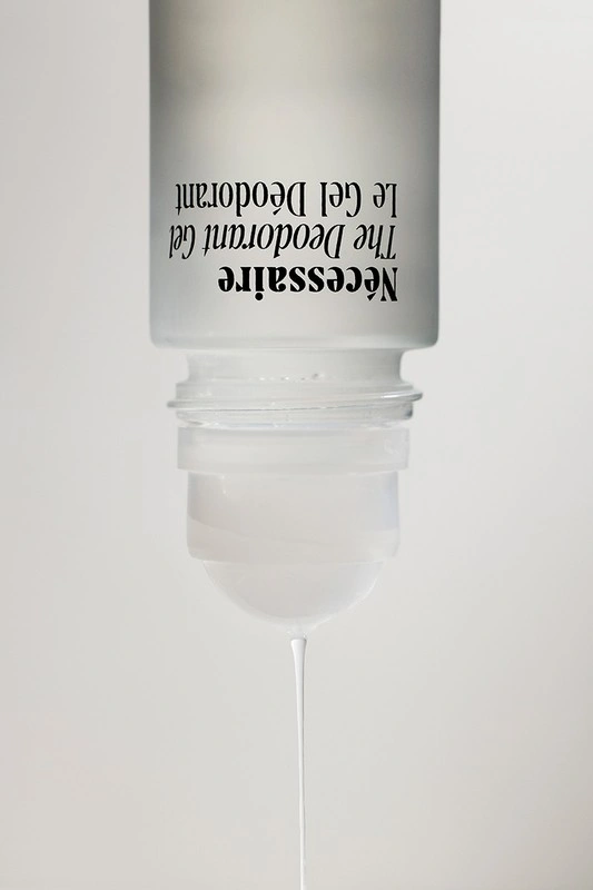 An inverted frosted glass deodorant bottle with black typography dripping a clear gel against a plain white background