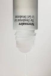 An inverted frosted glass deodorant bottle with black typography dripping a clear gel against a plain white background