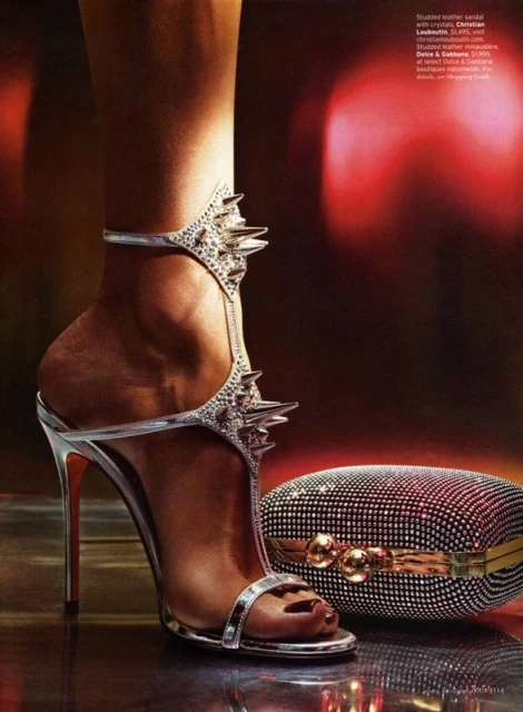 Fashion editorial: Silver stiletto heel with decorative spikes and a crystal encrusted clutch set against a deep red background.
