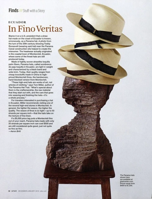 Stack of Panama hats atop a carved wooden bust on a small wooden table, presented in a studio shot for a magazine ad.
