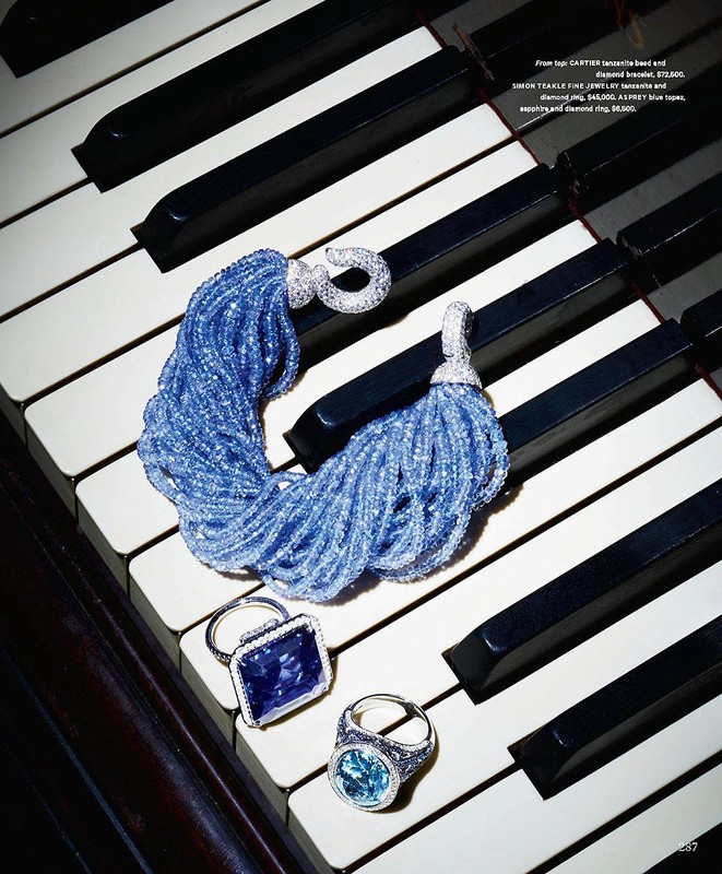 Close-up of fine jewelry on piano keys: a blue beaded bracelet, a sapphire ring, and a blue topaz ring on the black and white keys.