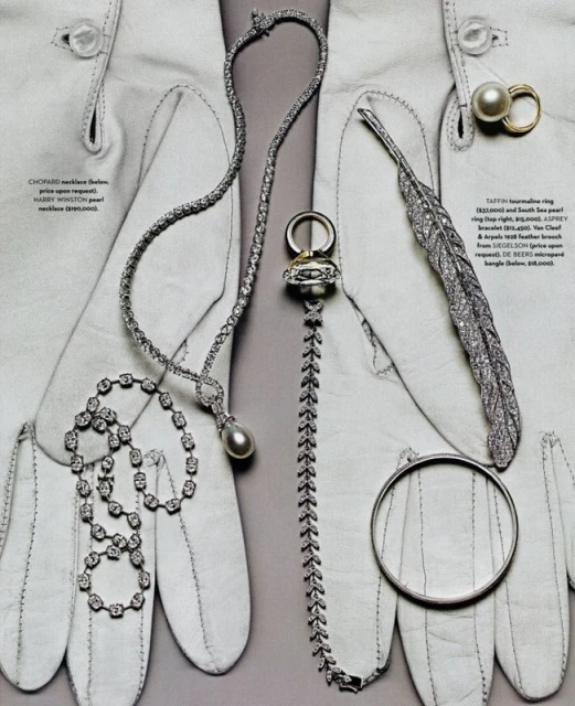 Editorial shot of an array of silver necklaces, rings, and a bangle artfully arranged on white leather gloves.