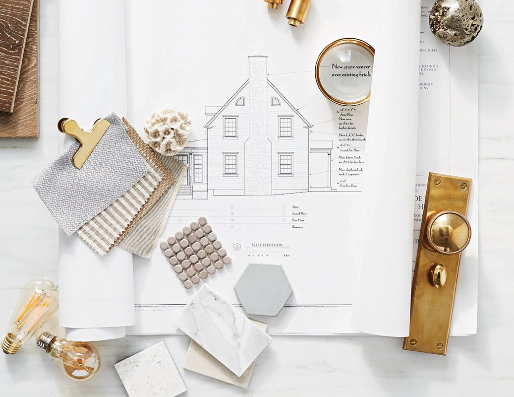 Interior design materials and architectural plan featuring tile samples, fabric swatches, lighting, and brass door hardware on a marble surface.