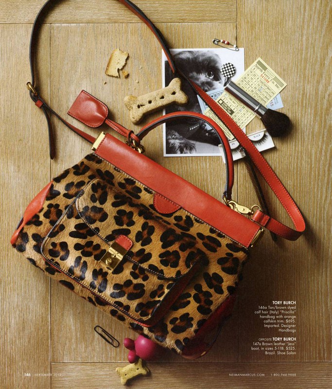 Leopard print and red leather handbag by Tory Burch with dog treats, makeup brush, and a photograph of a black dog.