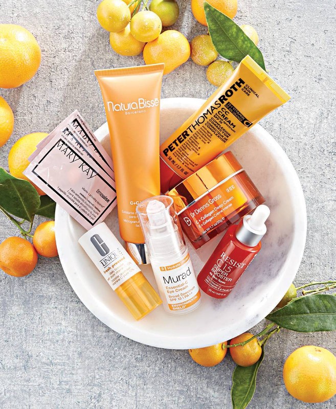 Cosmetic product assortment in white bowl. Variety of skincare items including creams, serums, and lotions from various brands. 