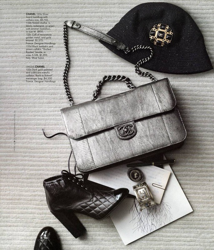 Still life of Chanel handbag, hat with brooch, and black leather booties. Fashion accessories on a textured neutral surface.