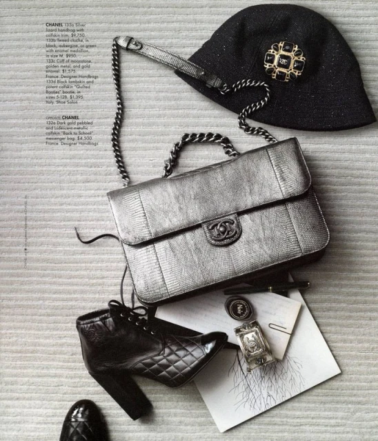 Still life of Chanel handbag, hat with brooch, and black leather booties. Fashion accessories on a textured neutral surface.