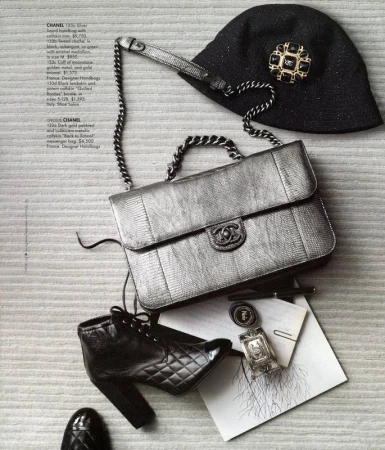 Still life of Chanel handbag, hat with brooch, and black leather booties. Fashion accessories on a textured neutral surface.