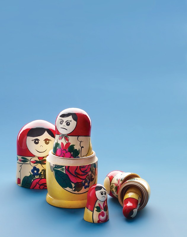 Colorful set of nesting Matryoshka dolls arranged on a light blue surface in a studio setting with soft, diffused lighting.