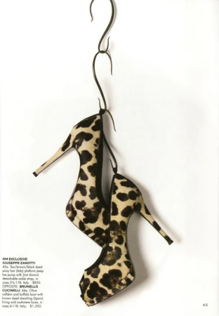 High heel shoes with black and tan animal print hanging from a dark metal s-hook against a plain white background.