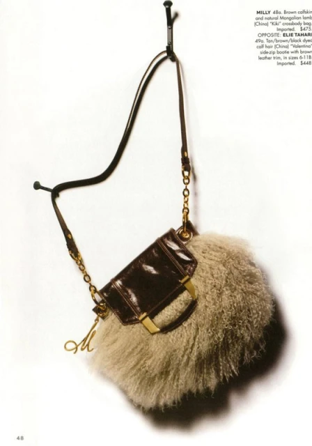 Brown leather and fur crossbody bag with a gold chain and metal logo charm hanging on a hook in a studio setting, fashion shoot.