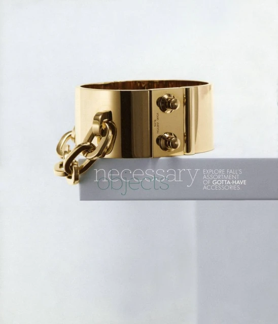 Gold-toned metal Louis Vuitton cuff bracelet with thick chain detail on a white shelf, studio lighting, and clean white background.