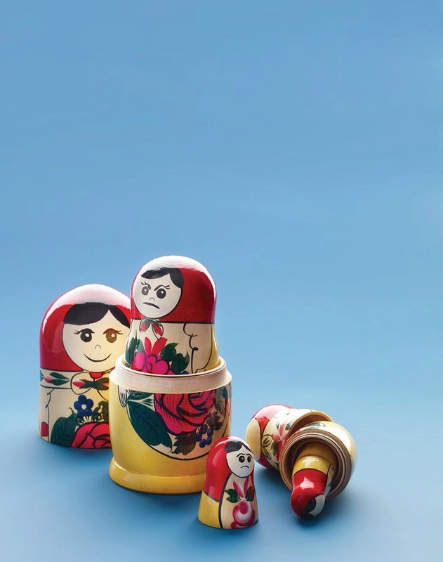 Set of colourful wooden Russian nesting dolls arranged on a solid blue surface with some pieces separated