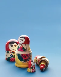 Set of colourful wooden Russian nesting dolls arranged on a solid blue surface with some pieces separated