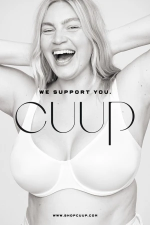 A woman smiles in a CUUP ad, wearing a white bra. She has blonde hair and white teeth. The background is simple, in black and white.