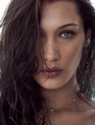 Close-up portrait of model Bella Hadid with dark wet hair partially covering her face and wearing a delicate necklace