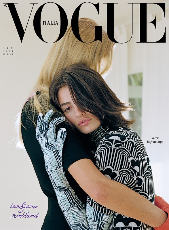 Vogue Italia cover featuring two adult females, one in a patterned top and gloves, embracing against a soft, neutral background.