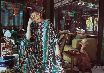 Woman in an ornate patterned kaftan with a high ponytail sitting in a richly decorated room styled by Lisa-marie Powell.