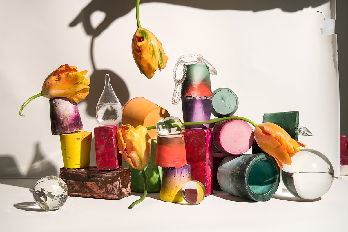 Still life of tulips and geometric shapes in a studio setting with diffused lighting casting shadows and creating a colorful composition.