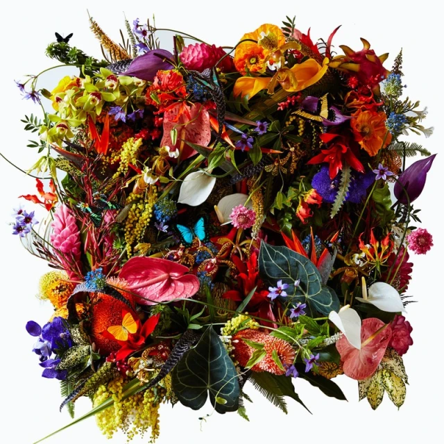 Vibrant square floral arrangement featuring a diverse mix of tropical flowers, leaves, and greenery on a clean, minimalist white background.