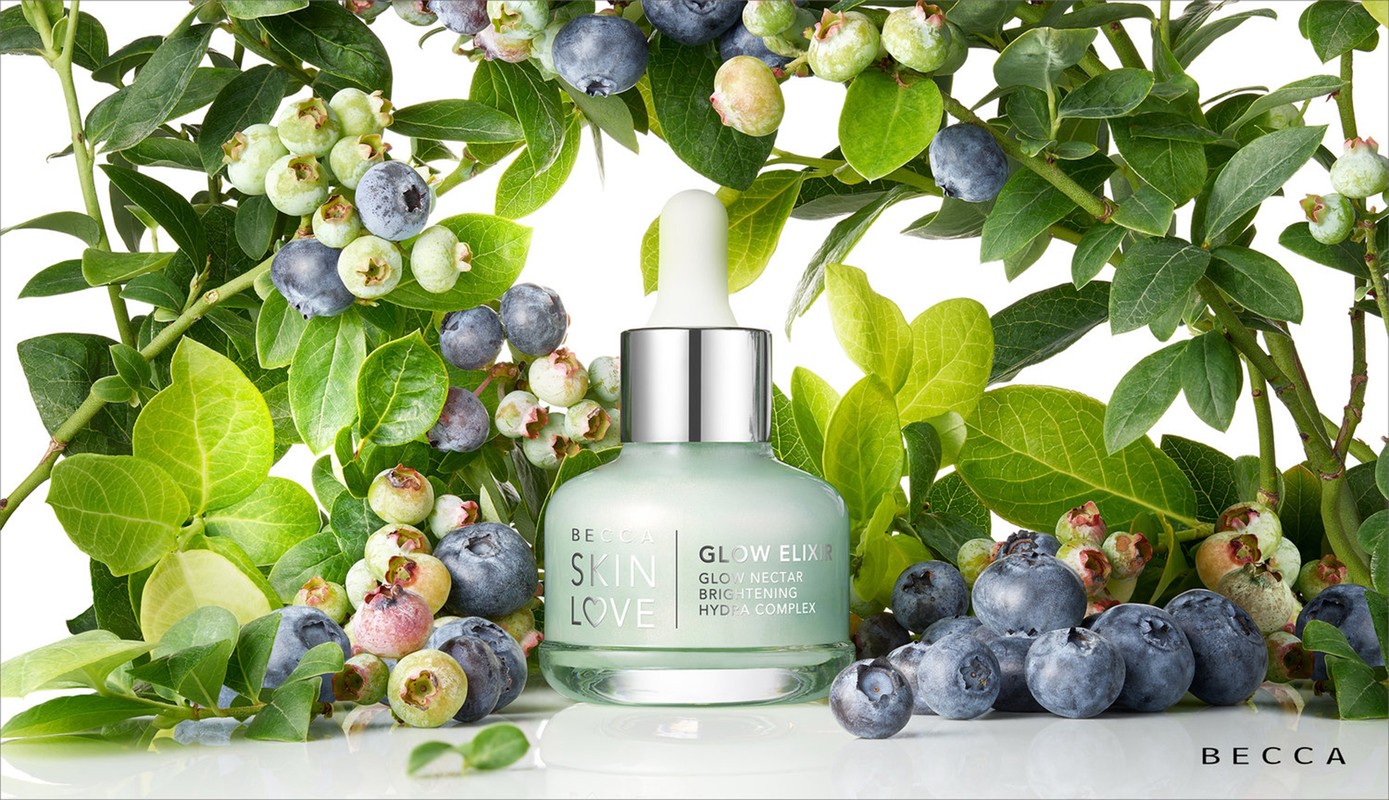 Beauty serum bottle with dropper surrounded by fresh blueberries and green leaves, showcasing natural skincare ingredients.