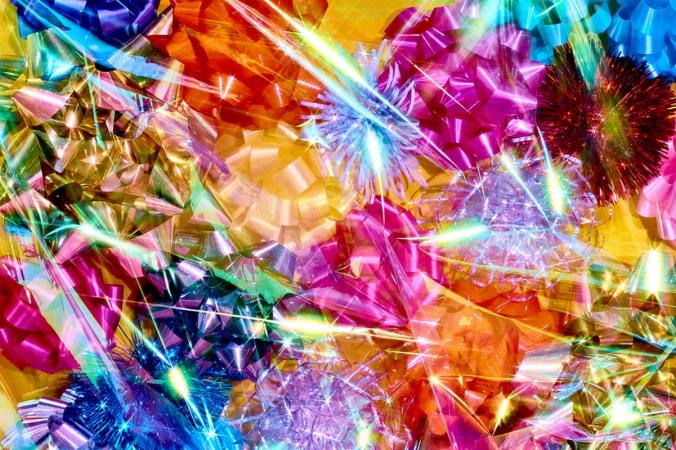 A vibrant close-up showcases a dazzling array of colorful metallic gift bows, interspersed with glittering light streaks against a yellow backdrop.
