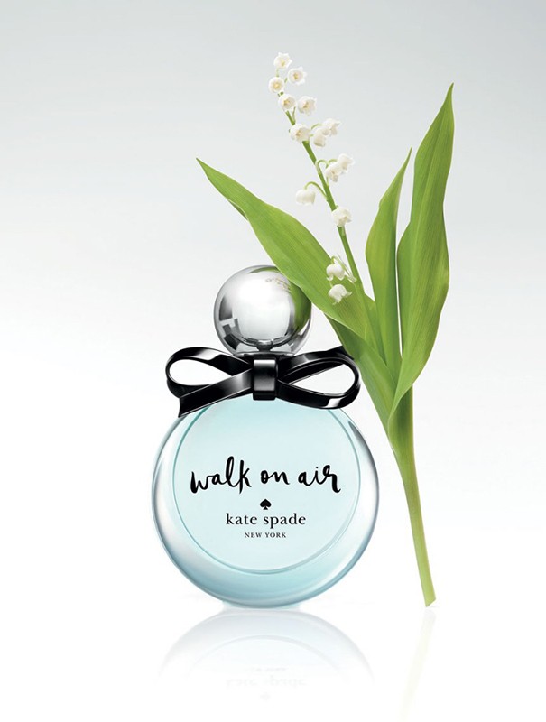 Perfume bottle by Kate Spade, Walk on Air scent, with lily of the valley on a white background. Glass bottle with black bow detail.