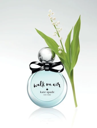 Perfume bottle by Kate Spade, Walk on Air scent, with lily of the valley on a white background. Glass bottle with black bow detail.