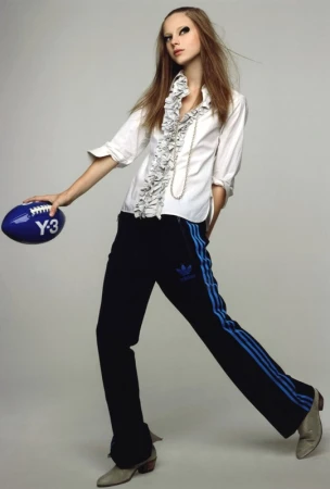 Full-length studio shot of a fashionable young adult female in casual wear, holding a blue football in a studio with a grey background.