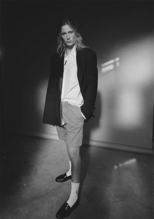 Monochrome portrait of a model in a dark oversized blazer, white shirt, and shorts styled by Lorri Sendel