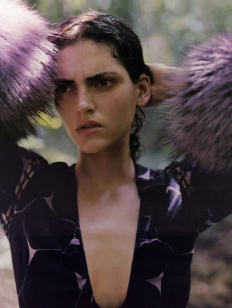 Close-up portrait of a woman with wet dark hair wearing a patterned dress with fluffy purple fur cuffs in Los Angeles.