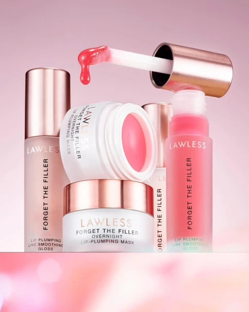 Cosmetic still life on a pink background featuring Lawless Forget The Filler lip-plumping gloss and overnight lip-plumping mask containers.