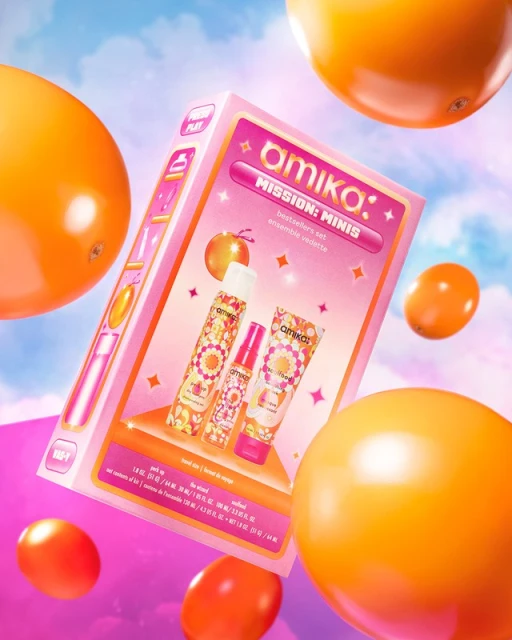 Amika 'Mission: Minis' set floating against a pink and blue gradient sky, surrounded by orange fruit. Beauty product and hair care.