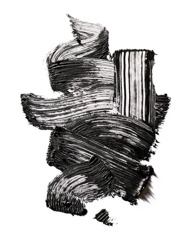 Abstract black smear of mascara brush strokes creating a textured pattern on a white backdrop, makeup concept for beauty ads.